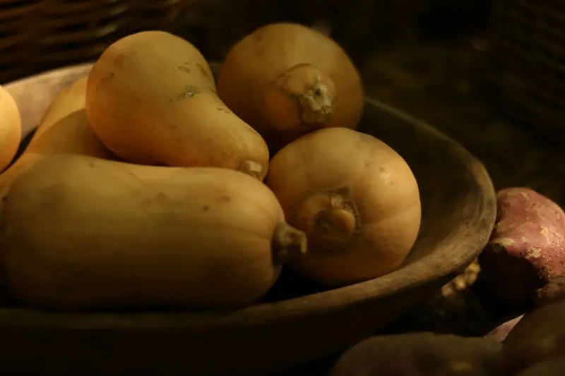 Des courges butternut dans une grande coupe en bois.