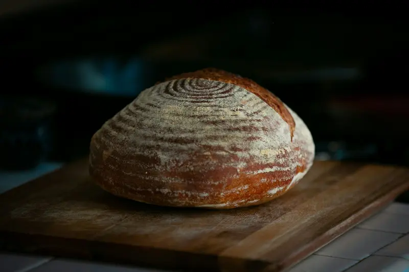 Une miche de pain au levain posée sur une planche en bois.